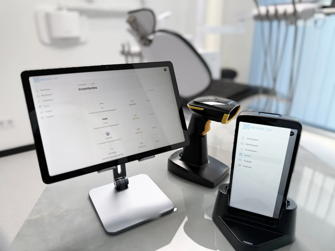 Tablet a Mediscan raktárnézetével, mellette 2D vonalkódolvasó töltőtalpon és kézi terminál, a háttérben kezelőszék